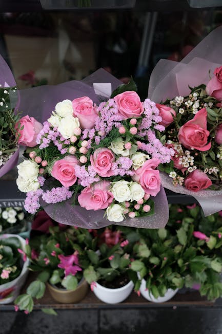 A floral arrangement featuring pink roses, white roses, and light pink statice flowers, intricately assembled into a bouquet. The flowers are fresh, with delicate petals and sturdy green stems, wrappe